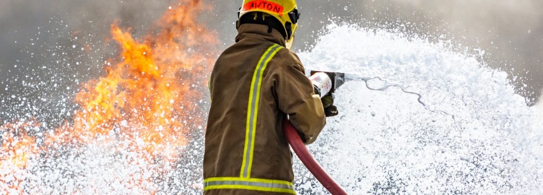 Uniformed firefighter attempting to extinguish a fire.