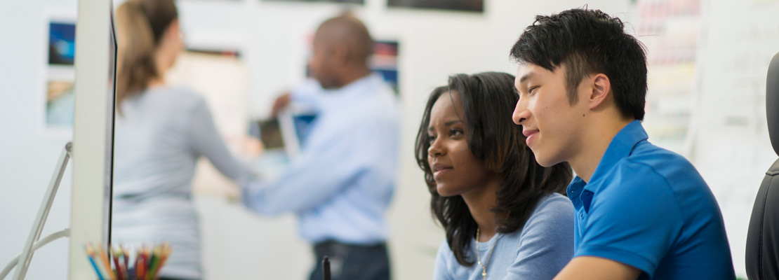 Two colleagues looking at a computer screen together.