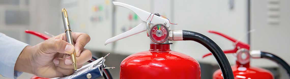 Someone inspecting fire extinguishers and making notes on a clipboard