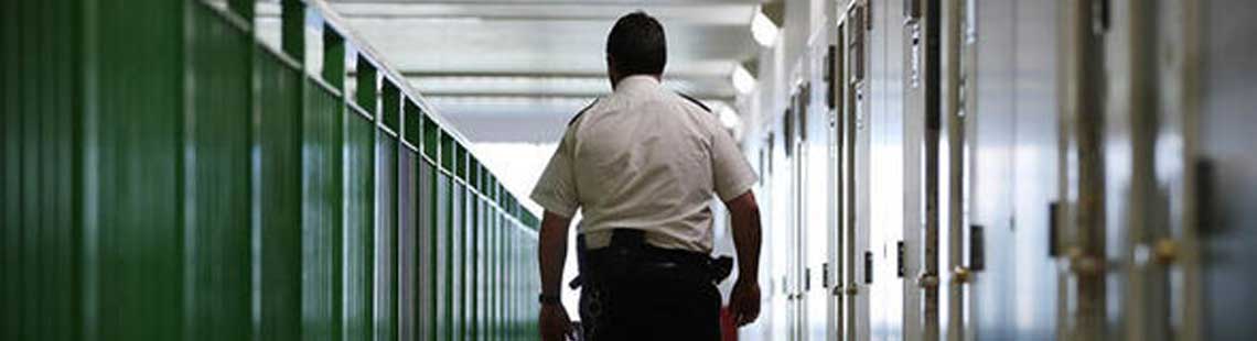 Back of prison officer walking through a prison corridor