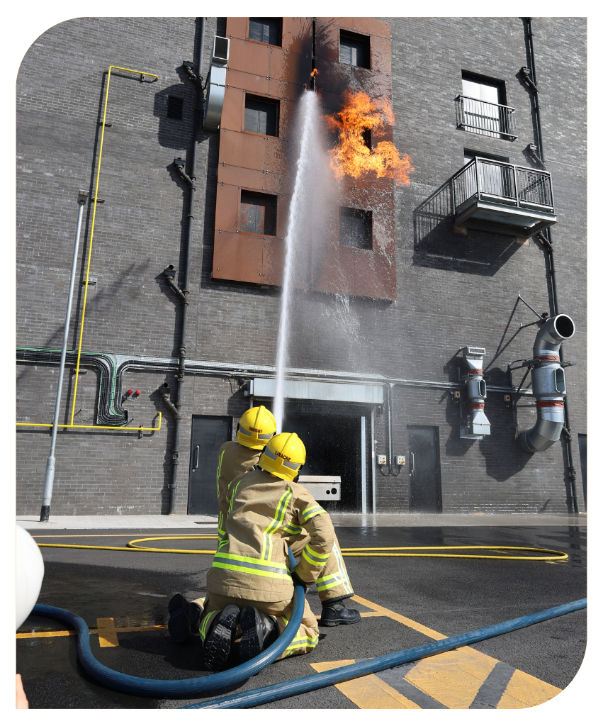 Two operational firefighters tackling a fire with a hose