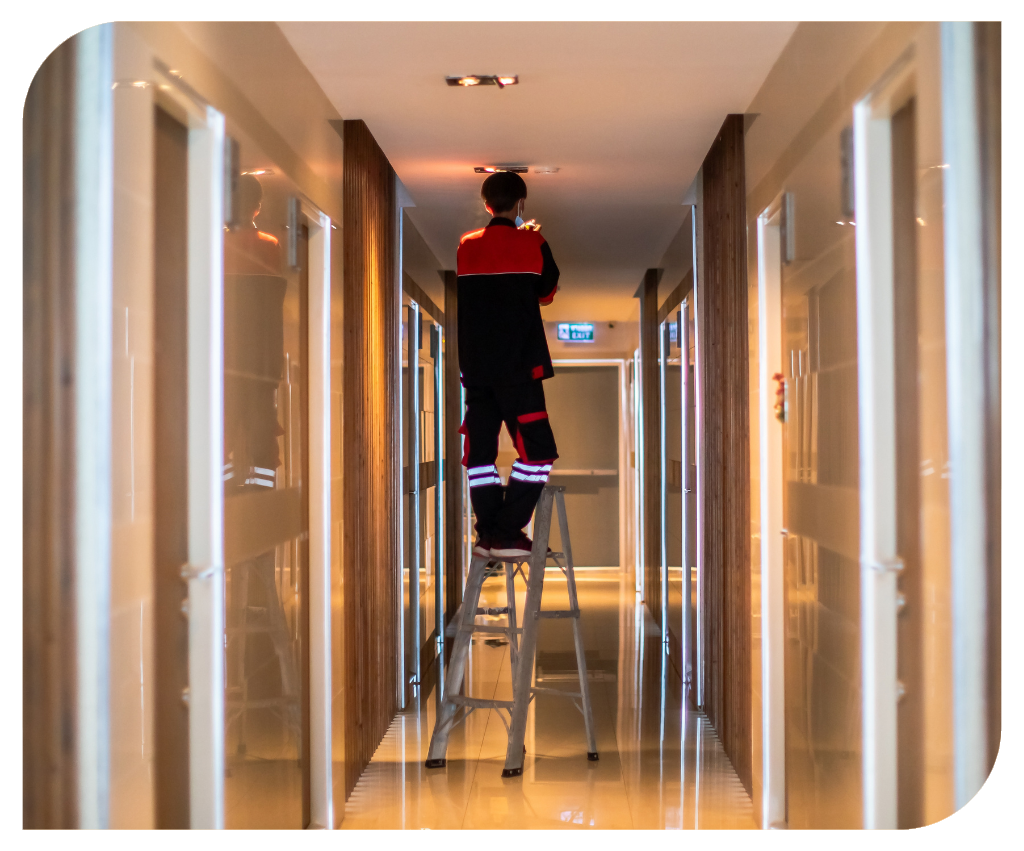 Technician is replacing or repair a smoke detector in an office building