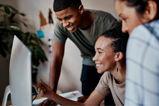 Colleagues smiling together looking at a computer screen